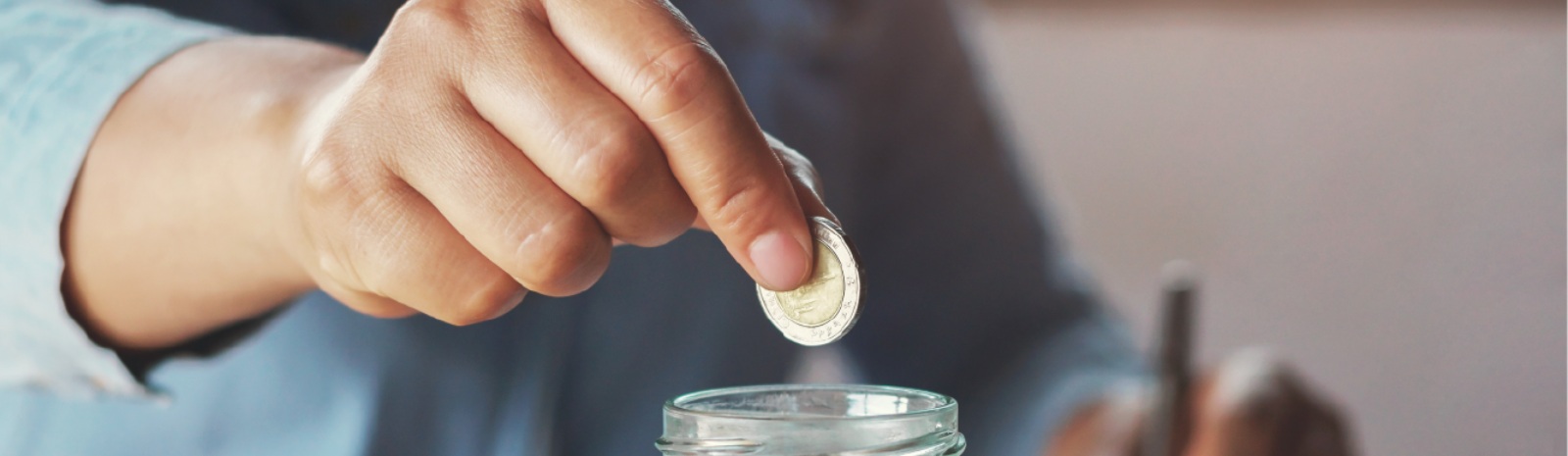 a person putting coins in a glass jar