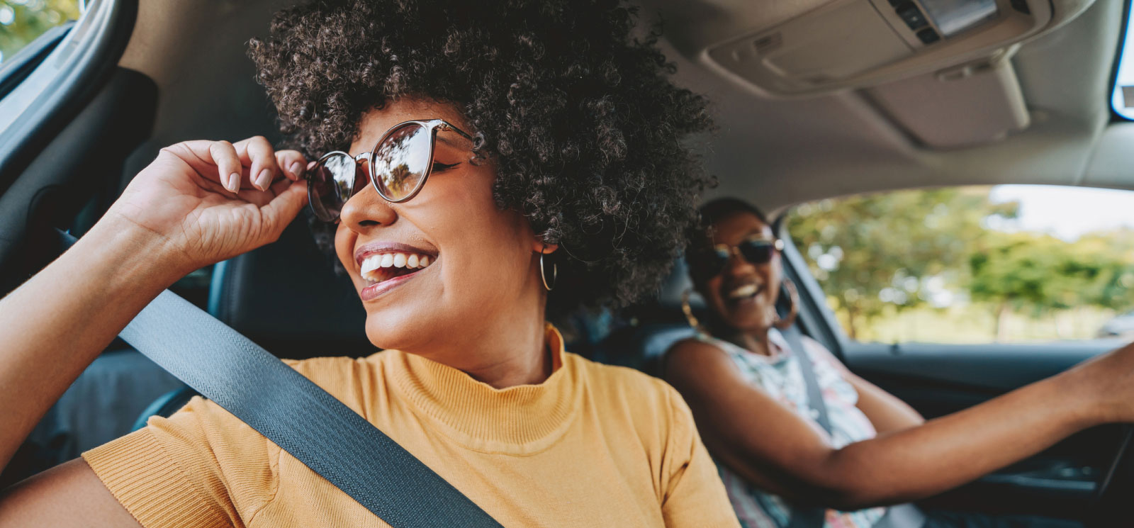 young woman wearing glasses and looking out a car window